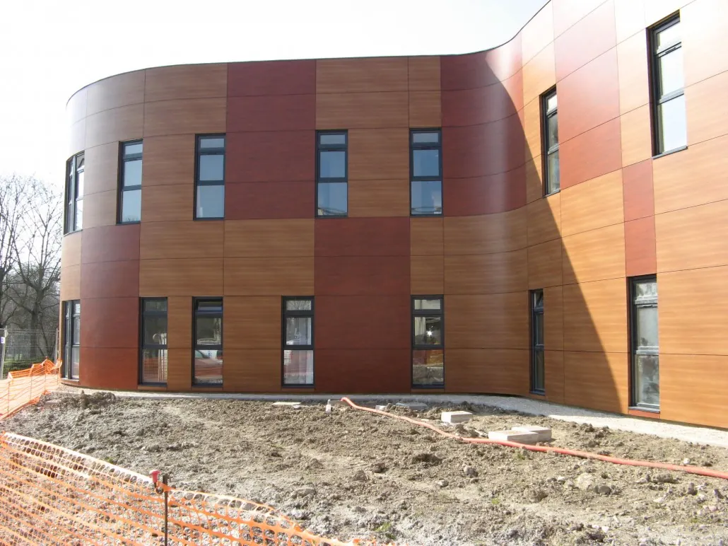 Bâtiment à façade arrondie habillée de panneaux de stratifié bois et rouge